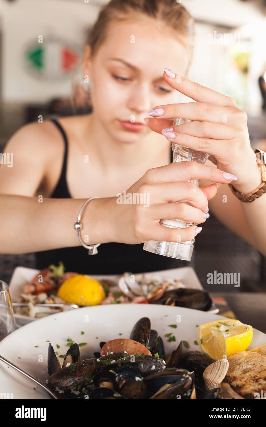 Junge schöne Mädchen fügt Salz in einem gemischten Meeresfrüchte-Salat Stockfoto
