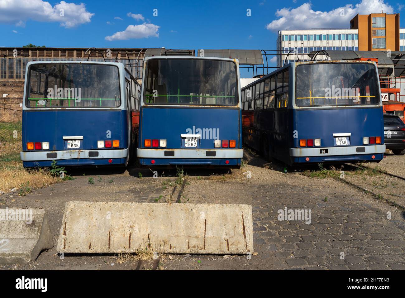 Budapest, Ungarn - 07.04.2021: Drei alte, ungenutzte blaue Busse stehen nebeneinander in einem Industriegebiet, von hinten geschossen. Stockfoto