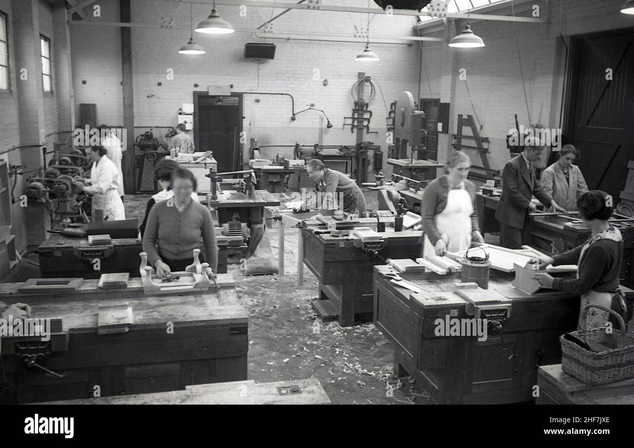 1936, historisch, Damen in einer Holzarbeiters-Klasse, die sie auf Arbeitstischen zeigt und einen männlichen Ausbilder, der einem von ihnen hilft, South East Essex Technical College Essex, England, Großbritannien. Stockfoto