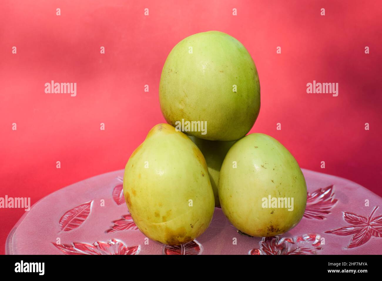 Frische und organische indische Früchte genannt Green Jujube oder Apple Jujube oder Ber Apfel. Grüne indische Jujuba-Pflaume Bora auf rotem Hintergrund Stockfoto