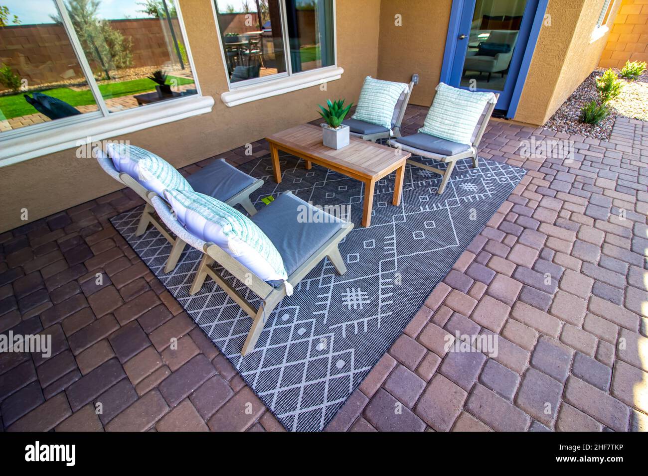 Hinterer Patio-Wohnbereich Mit Holztisch, Vier Stühlen Mit Kissen Und Dekorativem Teppich Stockfoto