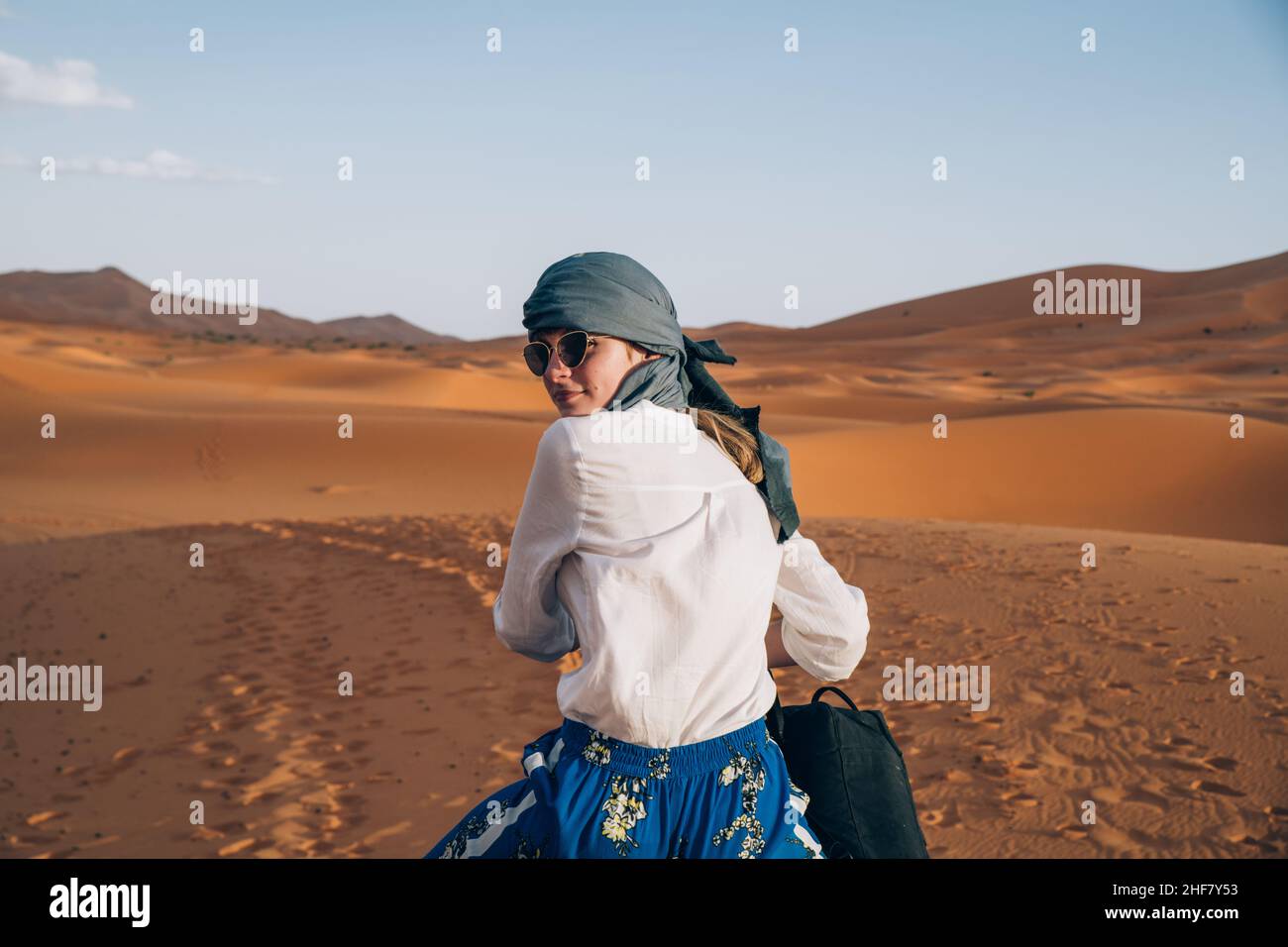 Das junge Mädchen mit Kopftuch und Sonnenbrille reitet auf einem Dromedar  durch die Wüste Erg chebbi Sahara in Marokko Stockfotografie - Alamy