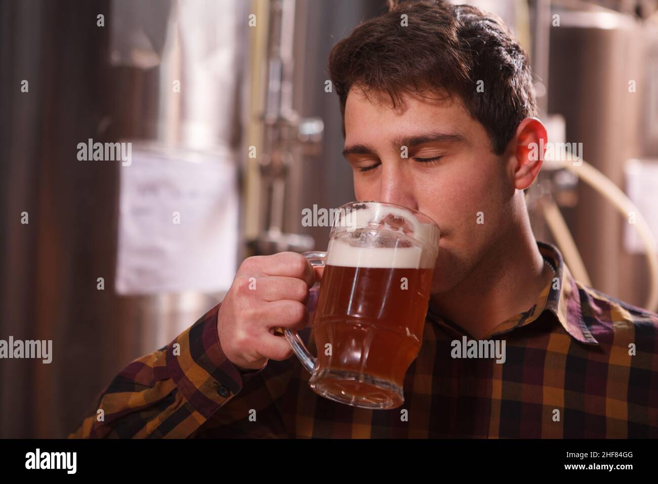 Nahaufnahme eines Mannes, der aromatisches frisch gebrautes Craft-Bier in einem Becher riecht Stockfoto