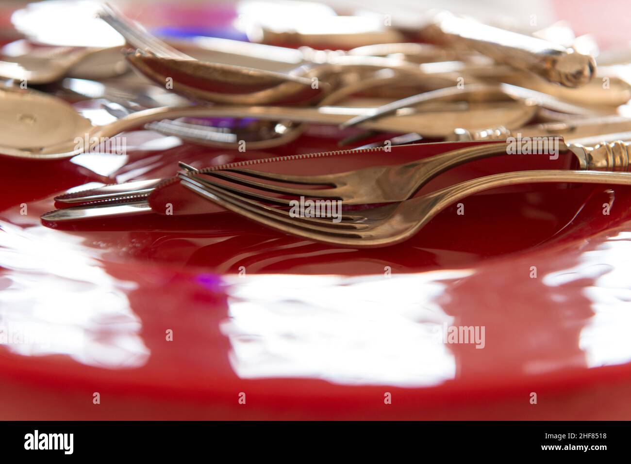 Besteck, rote Glasplatte, Messer, Gabel und Löffel Stockfoto