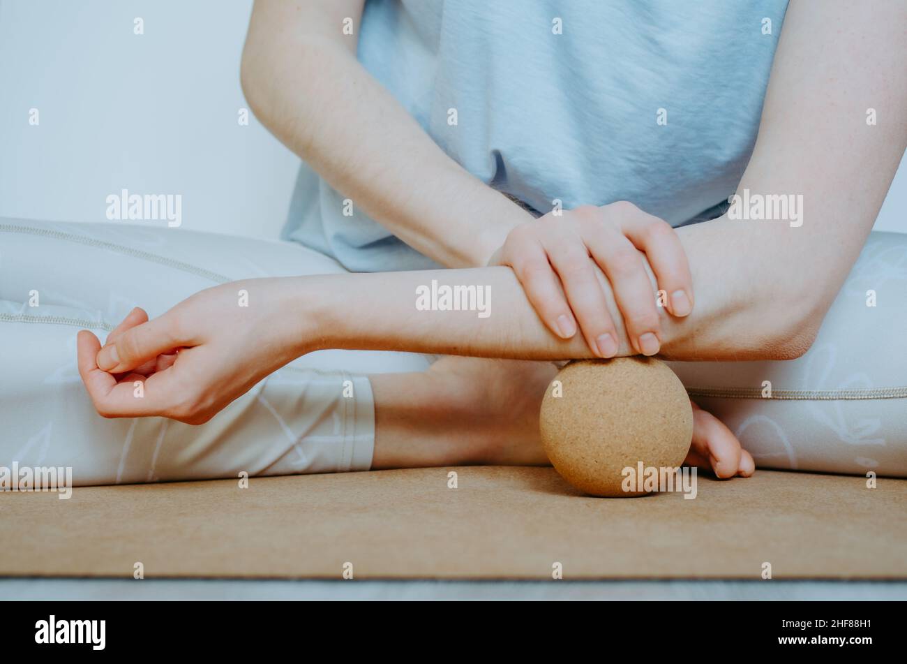 Unterarmmuskulatur myofasziale Freisetzung mit großer Kork-Massagekugel auf Kork-Yoga-Matte. Konzept: Selbstpflege zu Hause, nachhaltige Requisiten Stockfoto