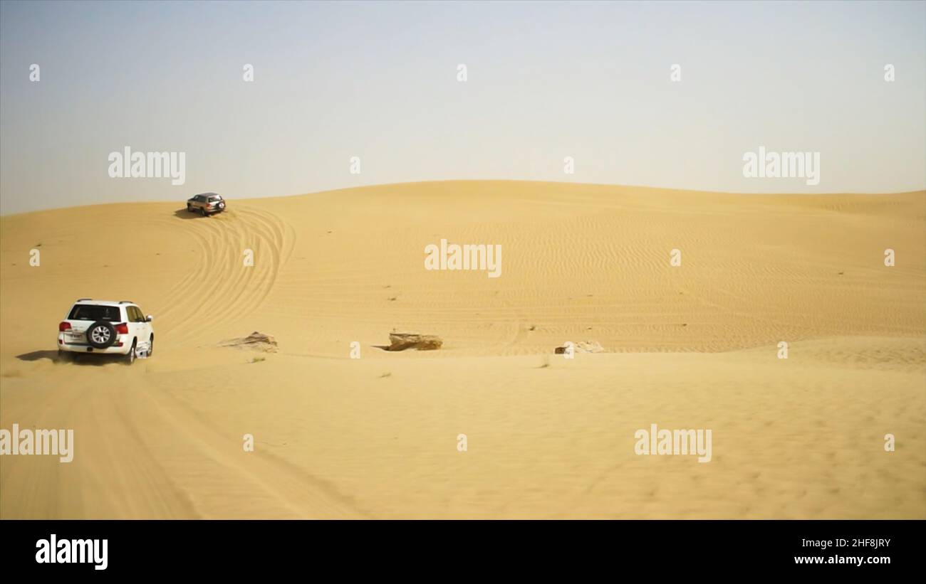 Luftaufnahme auf Offroad-Abenteuer mit SUV in der Arabischen Wüste bei Sonnenuntergang mit Skyline von Dubai oder Stadtbild. Wüstentouren mit SUV. Offroad-SUV beim Fahren Stockfoto