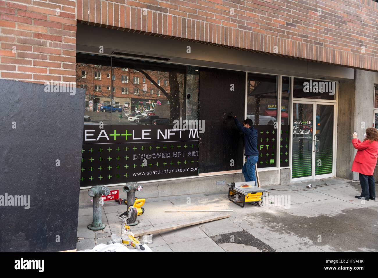 Seattle, USA. 14 Januar 2022. Bauunternehmer, die ein zerschmettertes Fenster im neuen NFT-Museum in Seattle im Viertel Belltown in der 2123-B 1st Ave. Betreten. Das Museum öffnet seine Tür in nur 6 Stunden. NTF's sind von Kontroversen umgeben, nicht-fungible Token digitale Kunst ist erheblich gewachsen, einige Stücke verkaufen sich für Millionen von Dollar. NFT-Unterstützer arbeiten daran, ein umweltfreundlicheres Modell für den Nachweis von Pfaden zu schaffen, das im Vergleich zum aktuellen Modell für den Nachweis von Arbeit steht. Gegner sind besorgt über den aktuellen Kohlenstoffausstoß von Kryptowährungen. Quelle: James Anderson/Alamy Live News Stockfoto