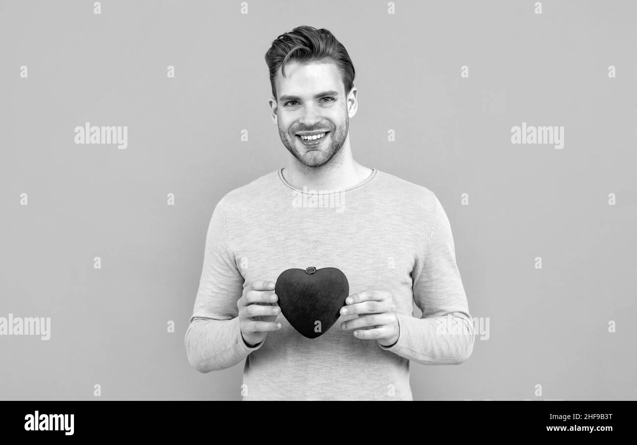 Mein Herz für dich. Hübscher Kerl lächelt mit rotem Herzen. Alles gute zum Valentinstag Stockfoto