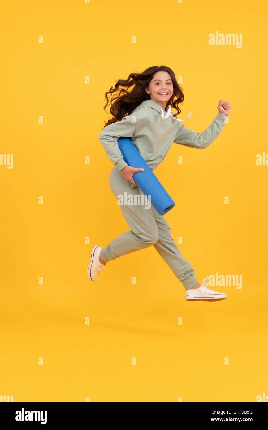 Frohes Kind in Sportswear Laufen mit Fitness-Matte. Fit Ihren Körper. Sport Teenager Mädchen Training. Stockfoto