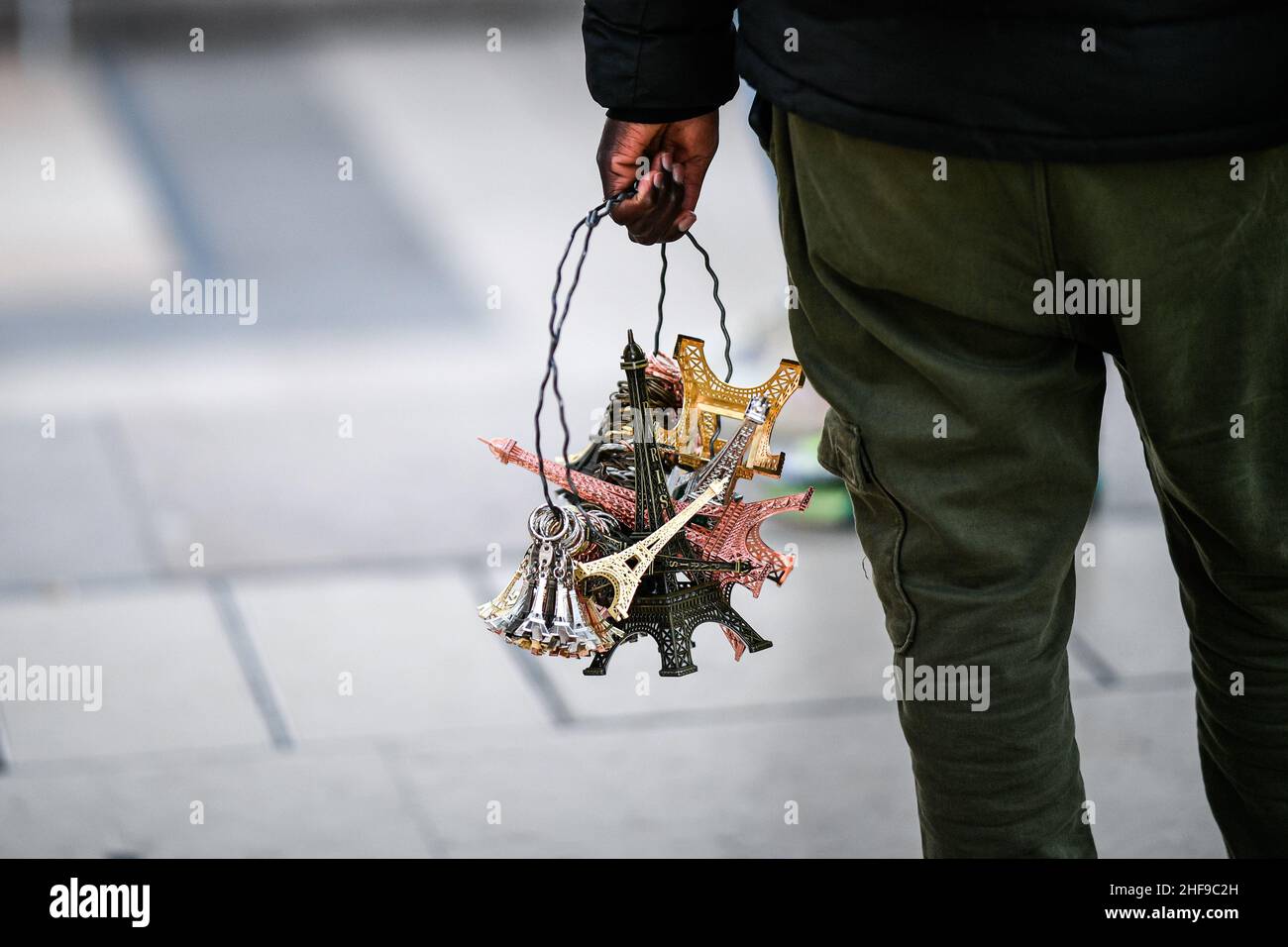 Die Abbildung zeigt einen Straßenhändler (oder Straßenhändler, auf Französisch „Venteurs a la sauvette“), der vor dem EIF Miniaturtürme verkauft Stockfoto