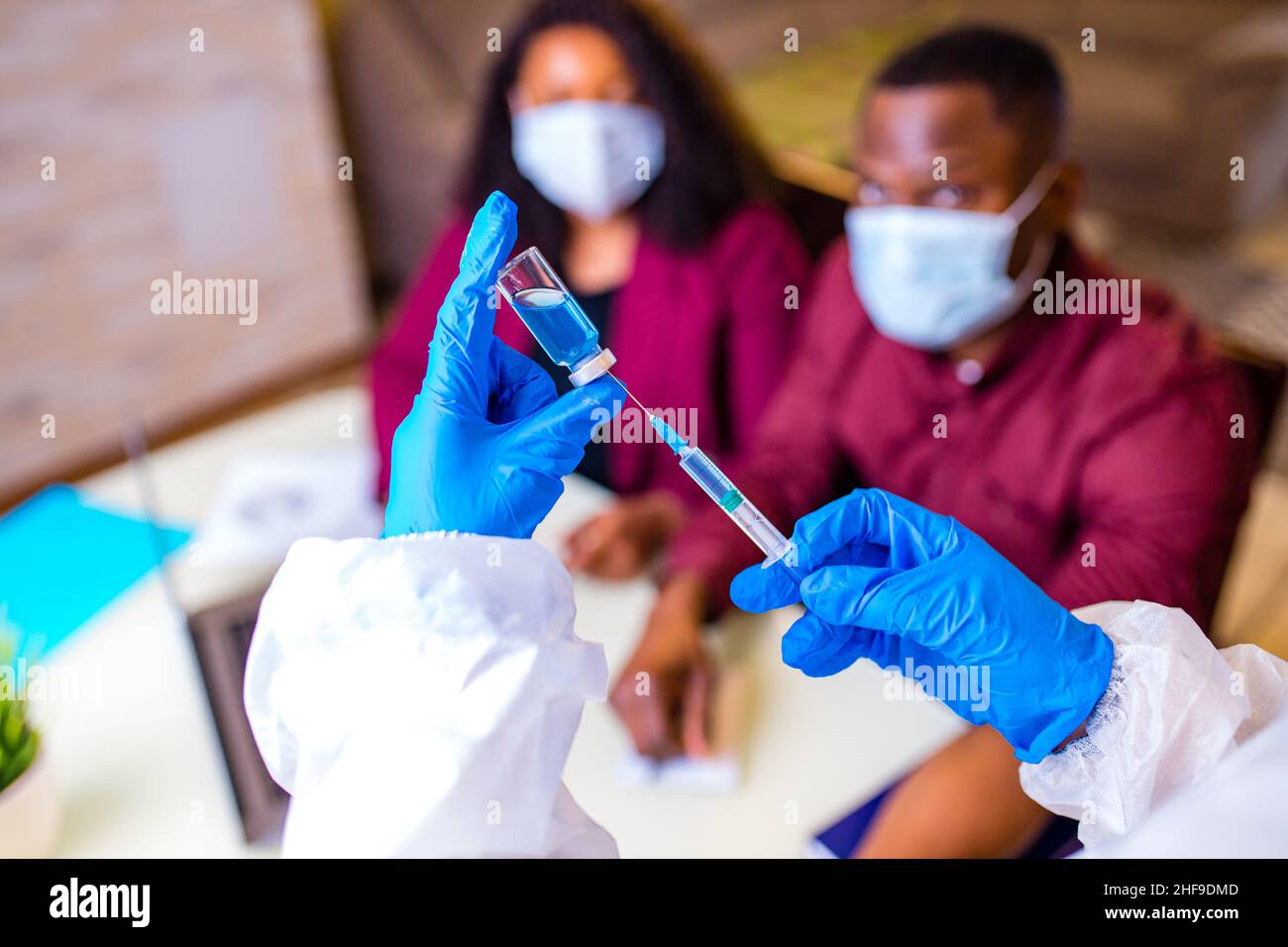 afroamerikanische Männer und Frauen tragen eine medizinische Maske und eine elegante jacke von marsha, die einen Coronavirus-Impfstoff erhält Stockfoto