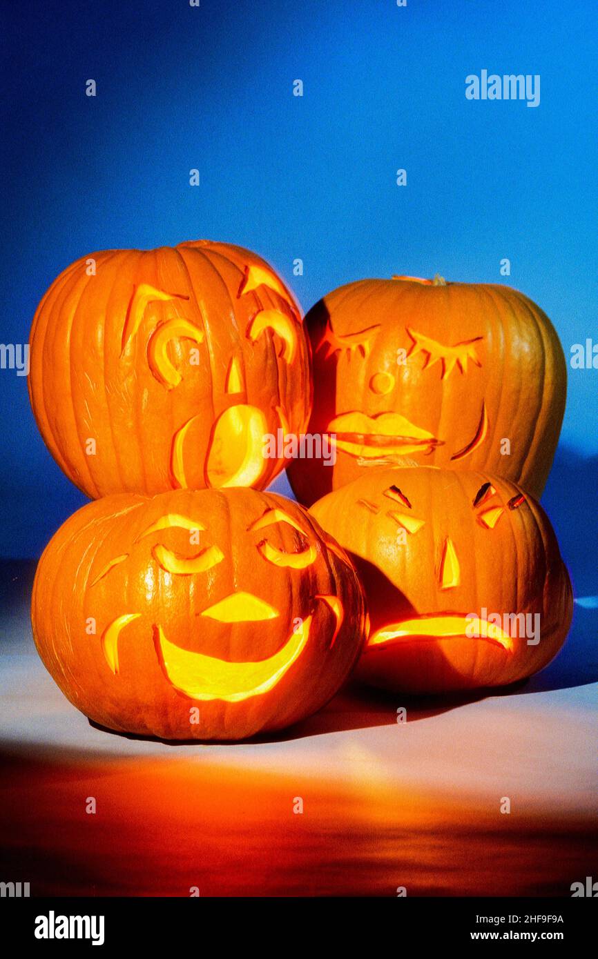 Vier leuchtende Halloween Jack-o-Laternen zeigen eine Vielzahl von Ausdrücken. Stockfoto