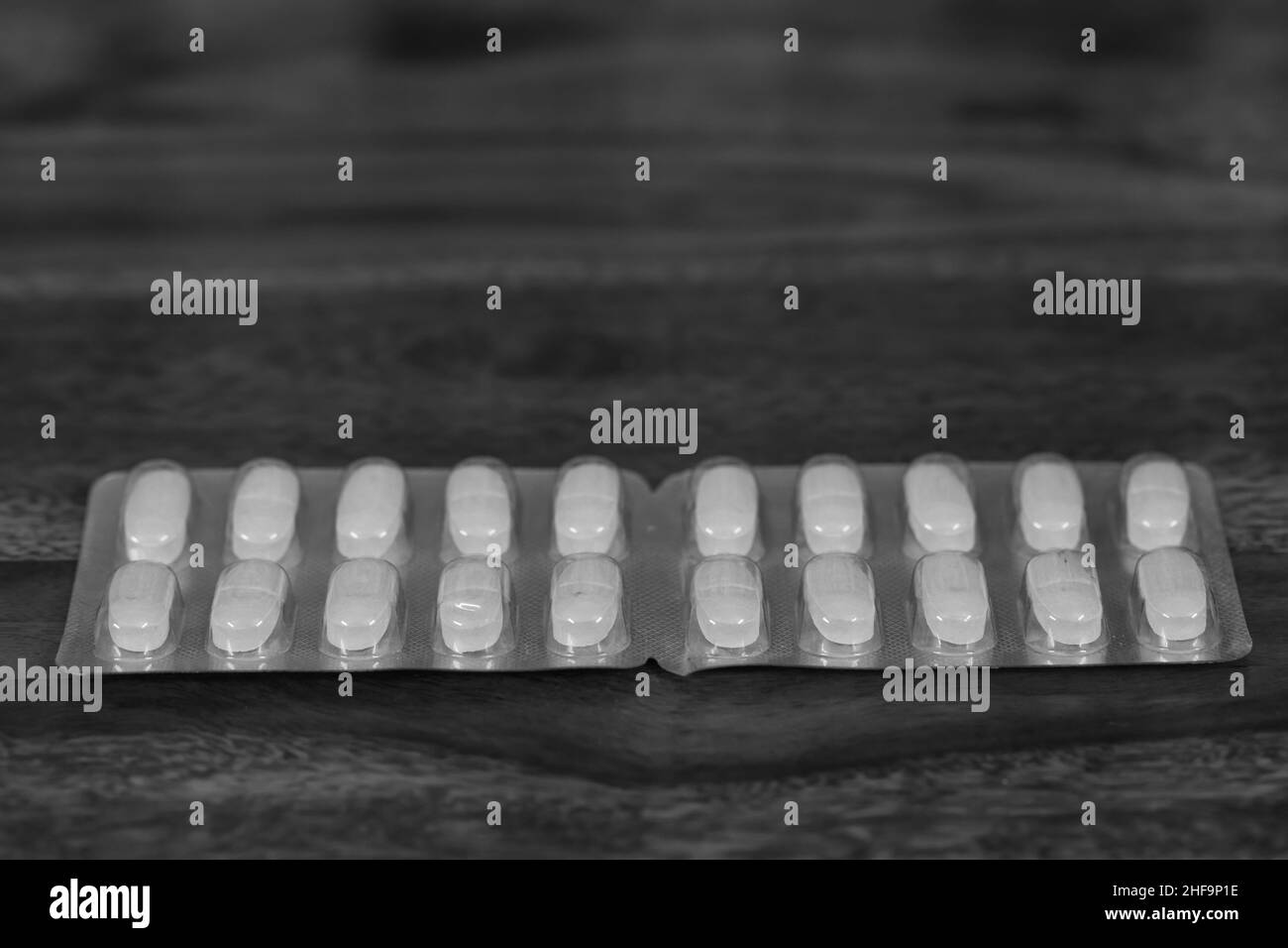 Ein Streifen allopathischer Medikamente, der auf einem Holztisch mit Platz für Kopien aufbewahrt wird Stockfoto