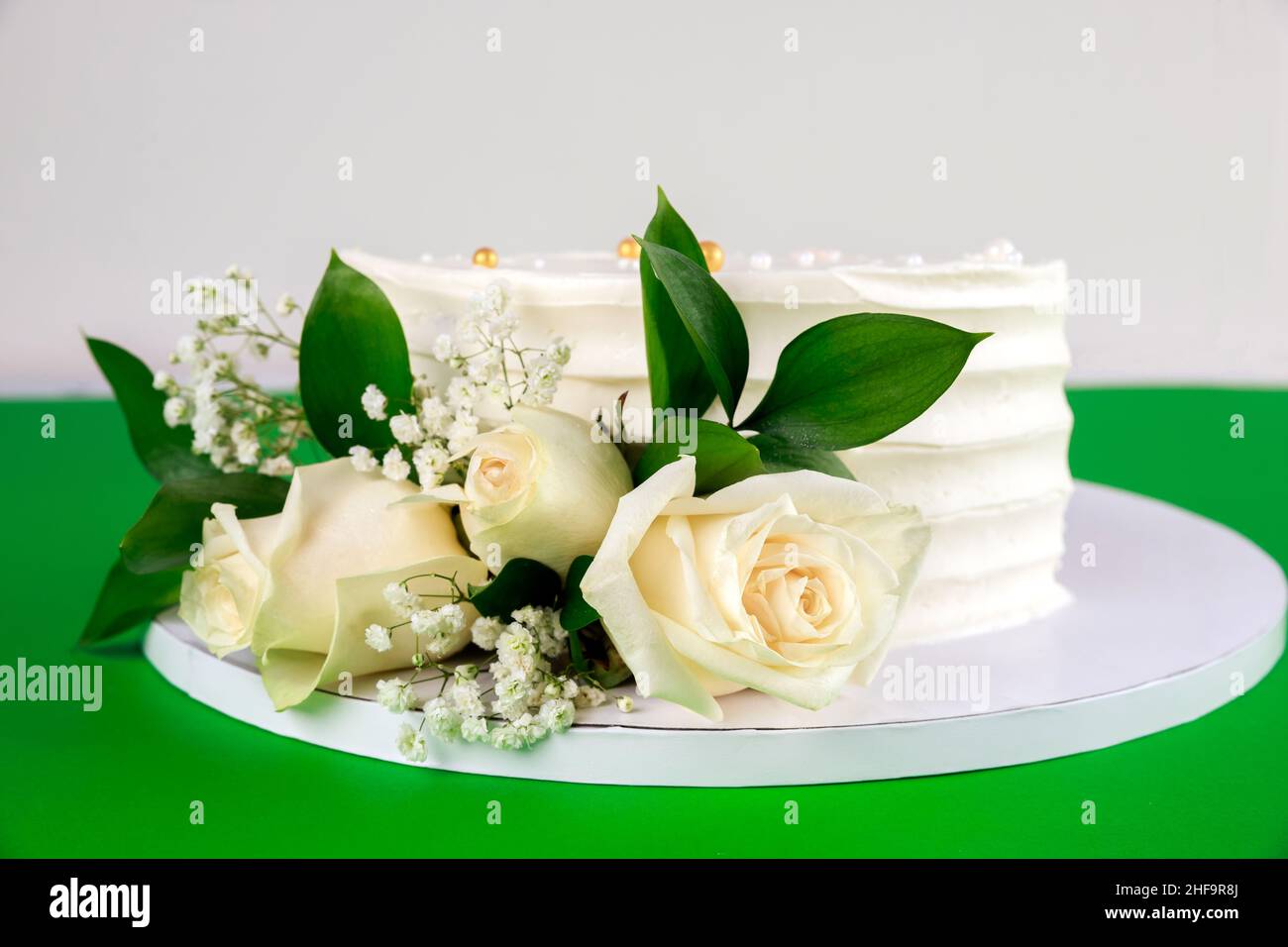 Hochzeitstorte mit weißen Rosen auf grünem Hintergrund. Nahaufnahme. Stockfoto