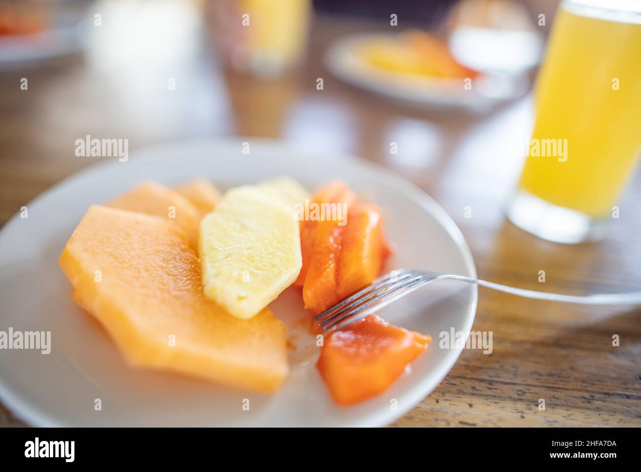 Köstliche Fruchtscheiben und Orangensaft auf einem Holztisch mit verschwommenem Hintergrund Stockfoto