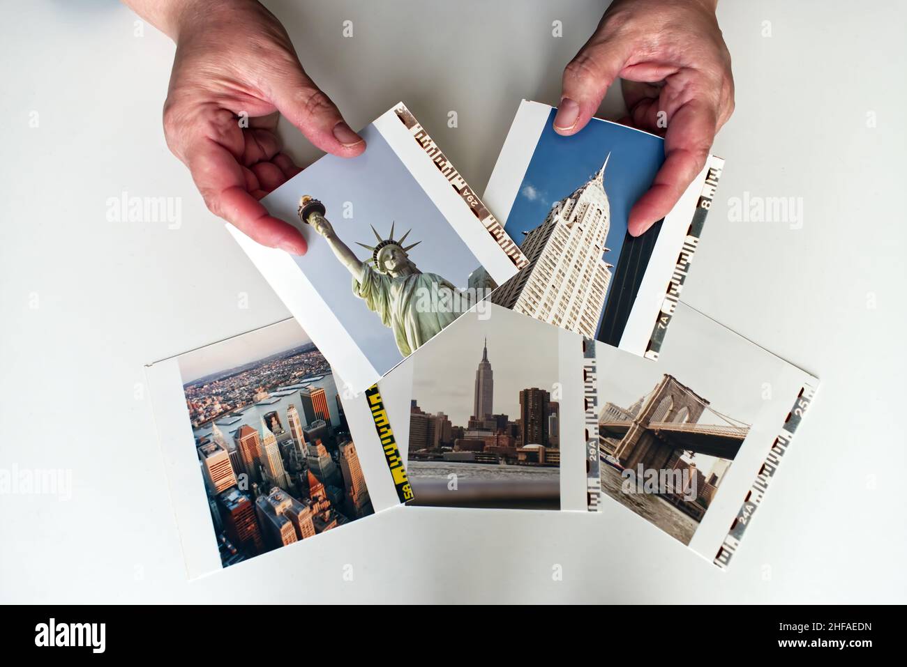 Frau Hände halten Fotoabzüge von New York City isoliert auf weißem Hintergrund. Reisen in den USA Konzept. Stockfoto