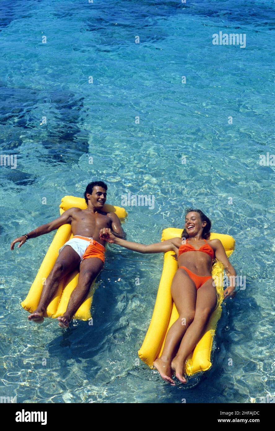 Junges Paar auf Seite Liebhaber auf Kunststoff schwimmende Matratze blau Meer Hintergrund hält Hände Stockfoto