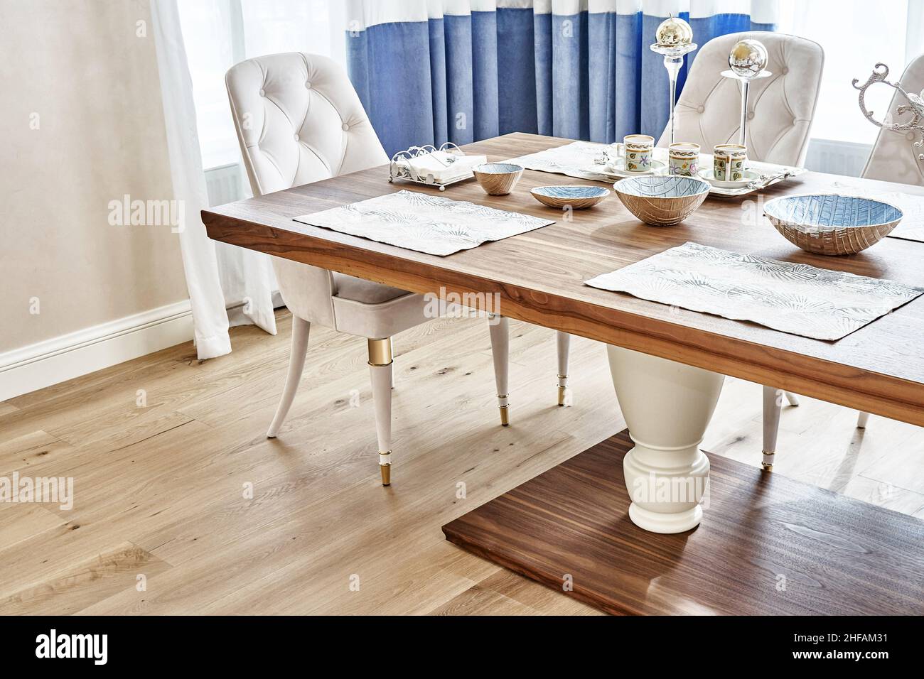Luxuriöser Vintage-Esstisch aus massivem Nussbaum- und Furnierholz mit festlichem Ambiente und Sesseln in der Nähe des Fensters in einem geräumigen Zimmer aus nächster Nähe Stockfoto