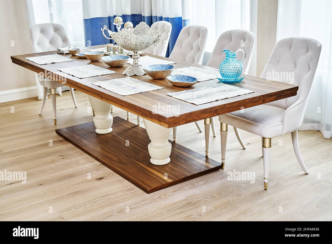 Luxuriöser Vintage-Esstisch aus massivem Nussbaum- und Furnierholz mit festlichem Ambiente und Sesseln in der Nähe des Fensters in einem geräumigen Zimmer Stockfoto