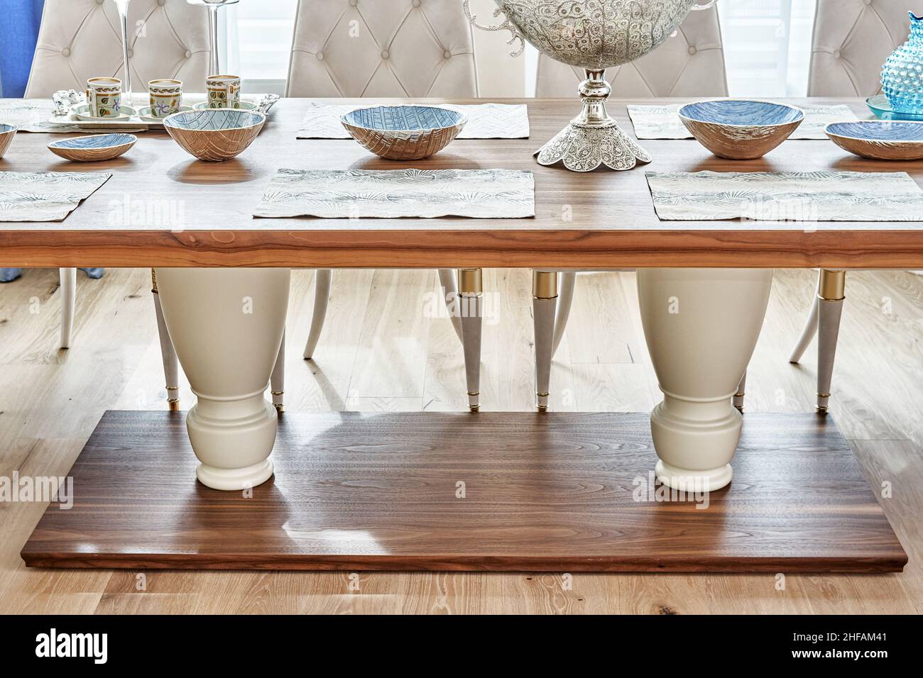 Luxuriöser Vintage-Esstisch aus massivem Nussbaum- und Furnierholz mit festlichem Ambiente und Sesseln in der Nähe des Fensters in einem geräumigen Zimmer aus nächster Nähe Stockfoto