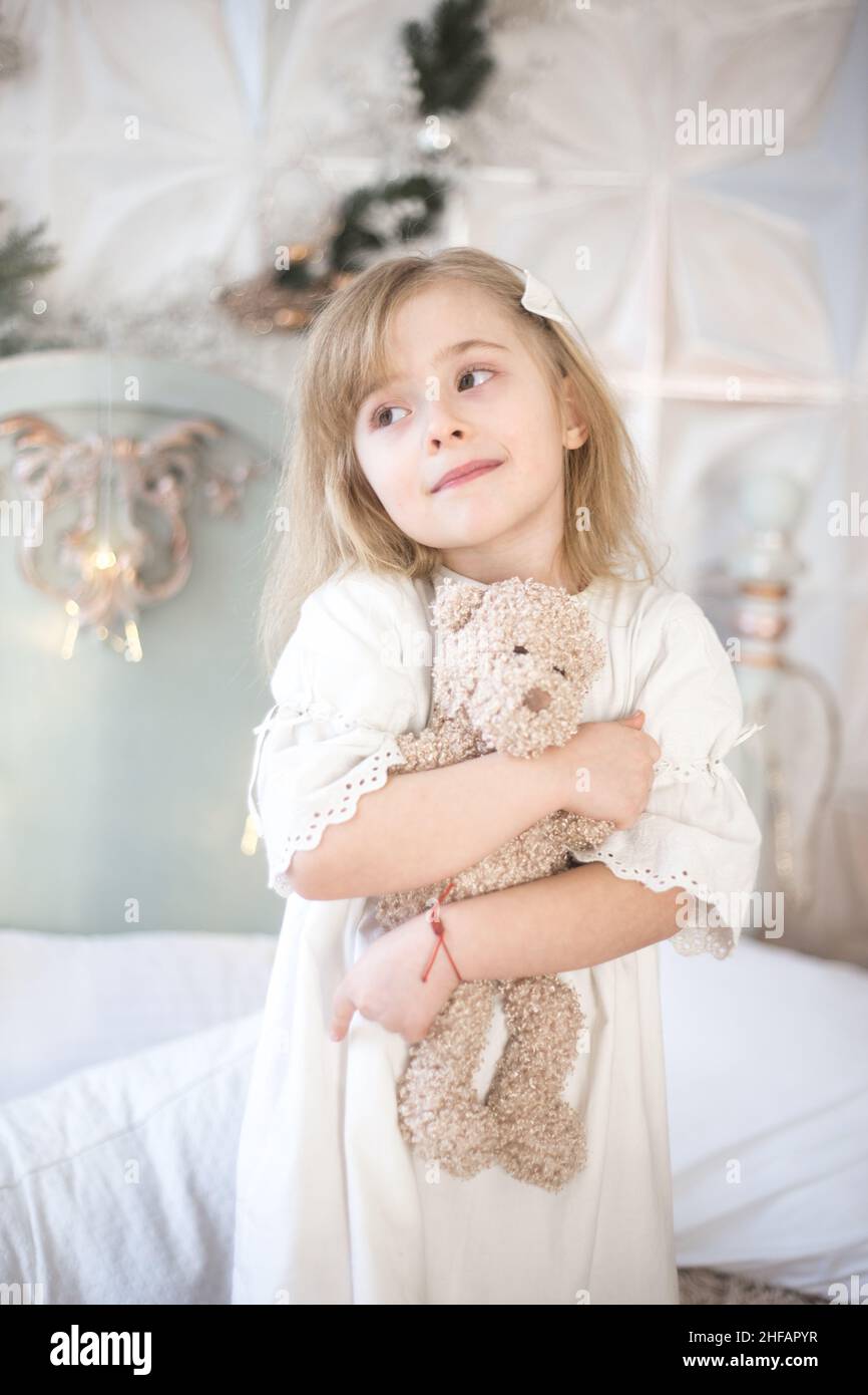Das kleine Mädchen und ihr Teddybär am Morgen im Schlafzimmer. Retro-Style. Stockfoto
