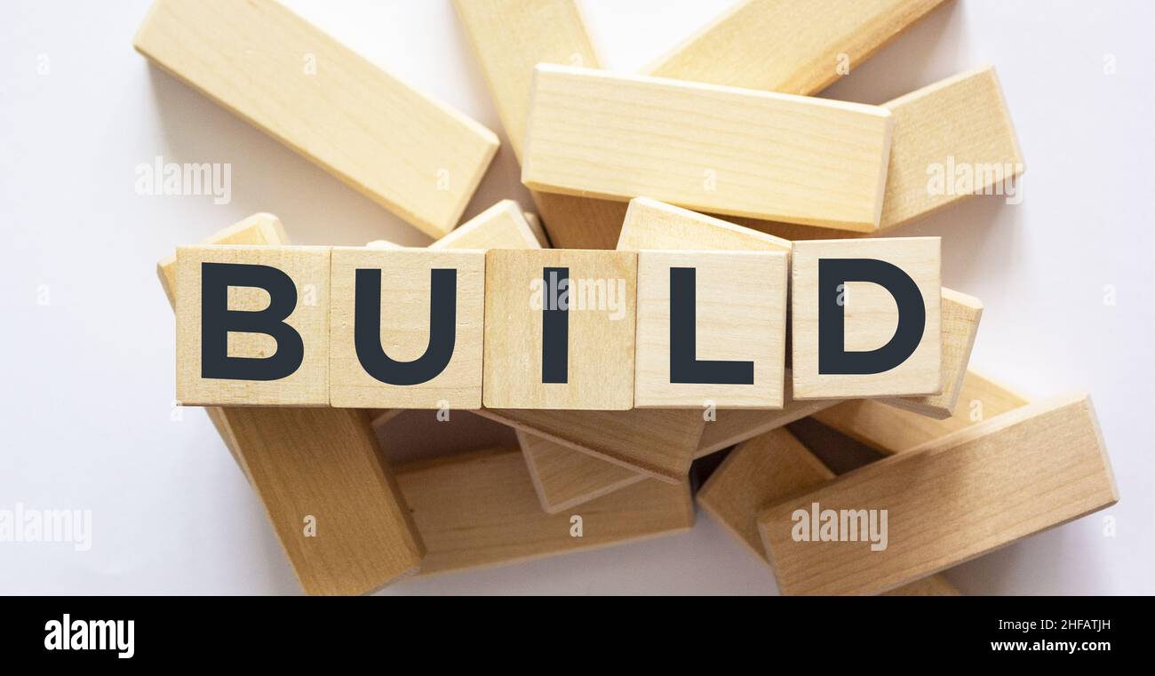 Bauen Wort in Holzwürfeln und weißem Hintergrund geschrieben Stockfoto