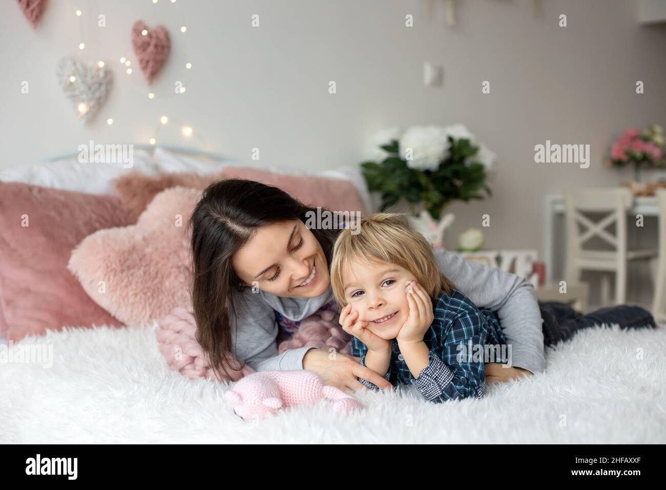 Schöne blonde Junge und Mutter, im Bett liegend, versteckt unter Decke, genießen Familie Zeit zusammen Stockfoto