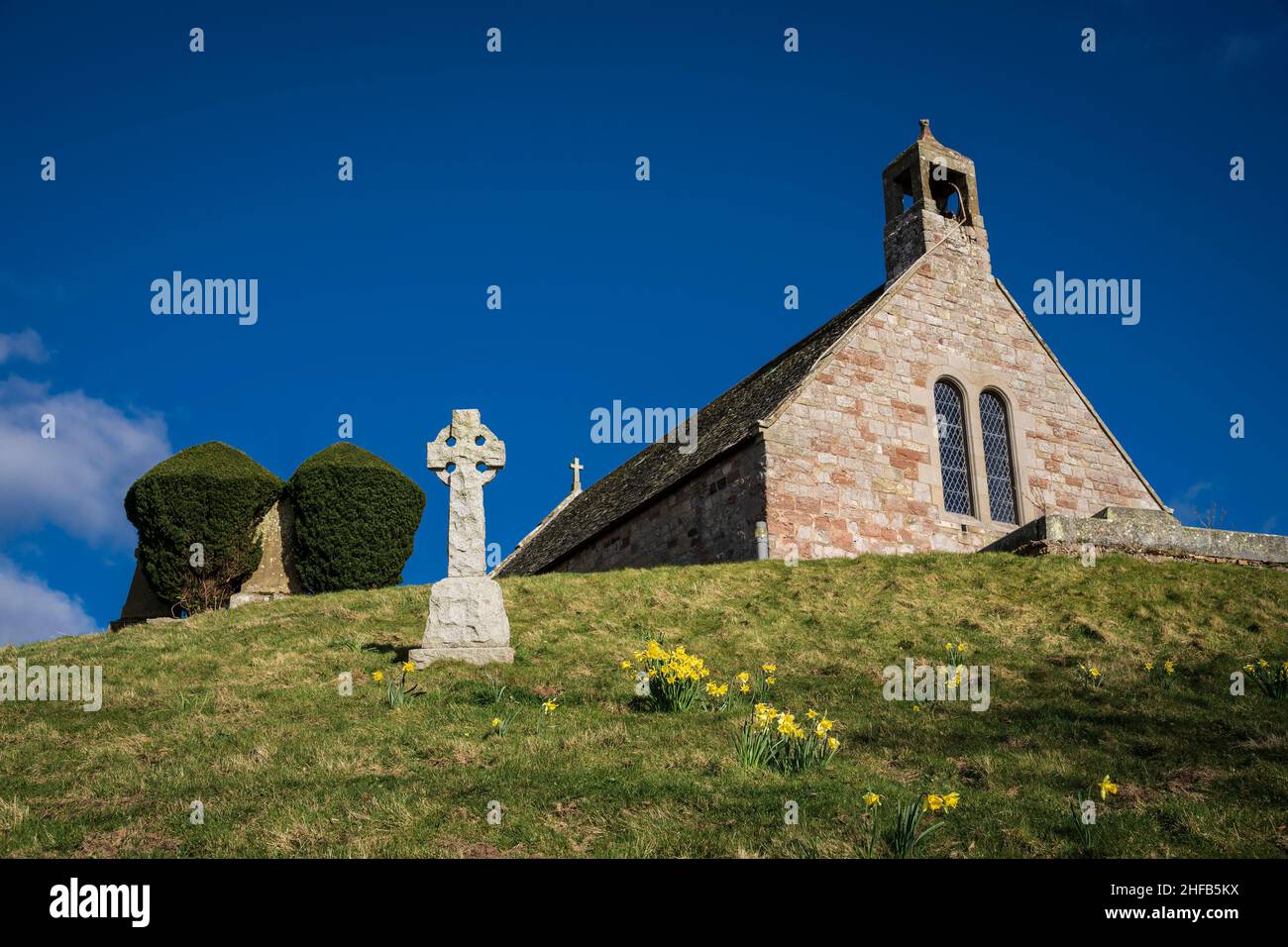 Linton Kirk, in der Nähe von Moreschlacht, Kelso, Scottish Borders. Mit einem keltischen Kreuz-Denkmal und Narzissen am ersten Apriltag. Stockfoto