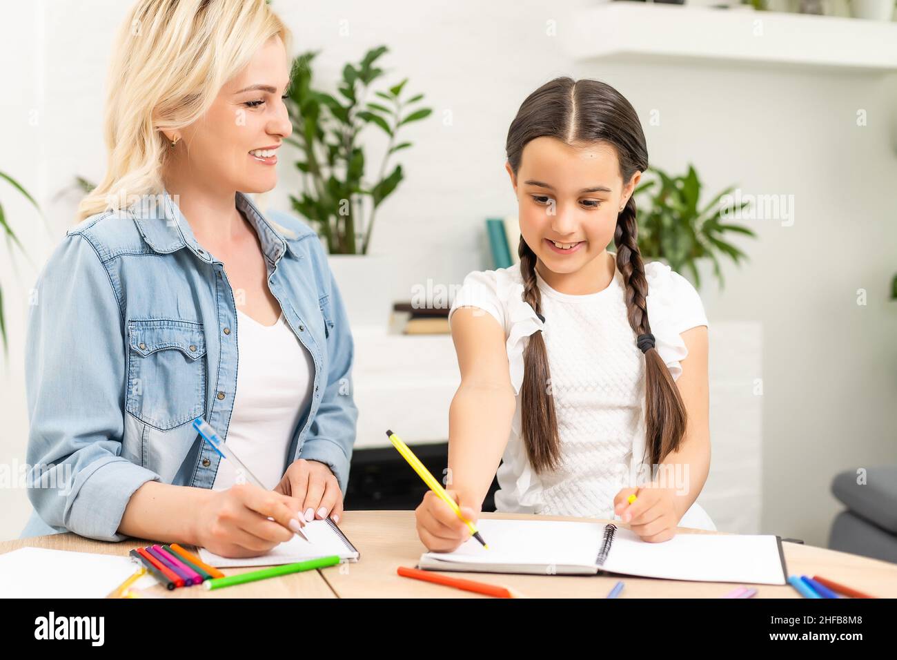 Schülerin und Mutter zusammen Hausaufgaben in Haus Stockfoto