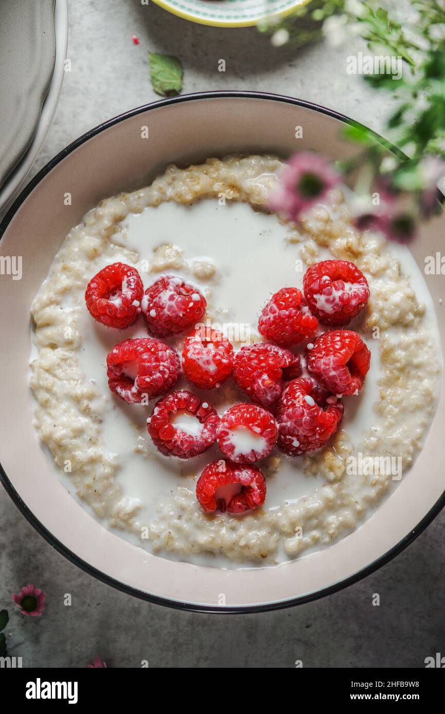 Nahaufnahme der Haferflocken-Schüssel mit Herz von Himbeeren. Romantisches Frühstück mit gesunden Zutaten. Herzförmige Beerenfrüchte. Draufsicht. Stockfoto