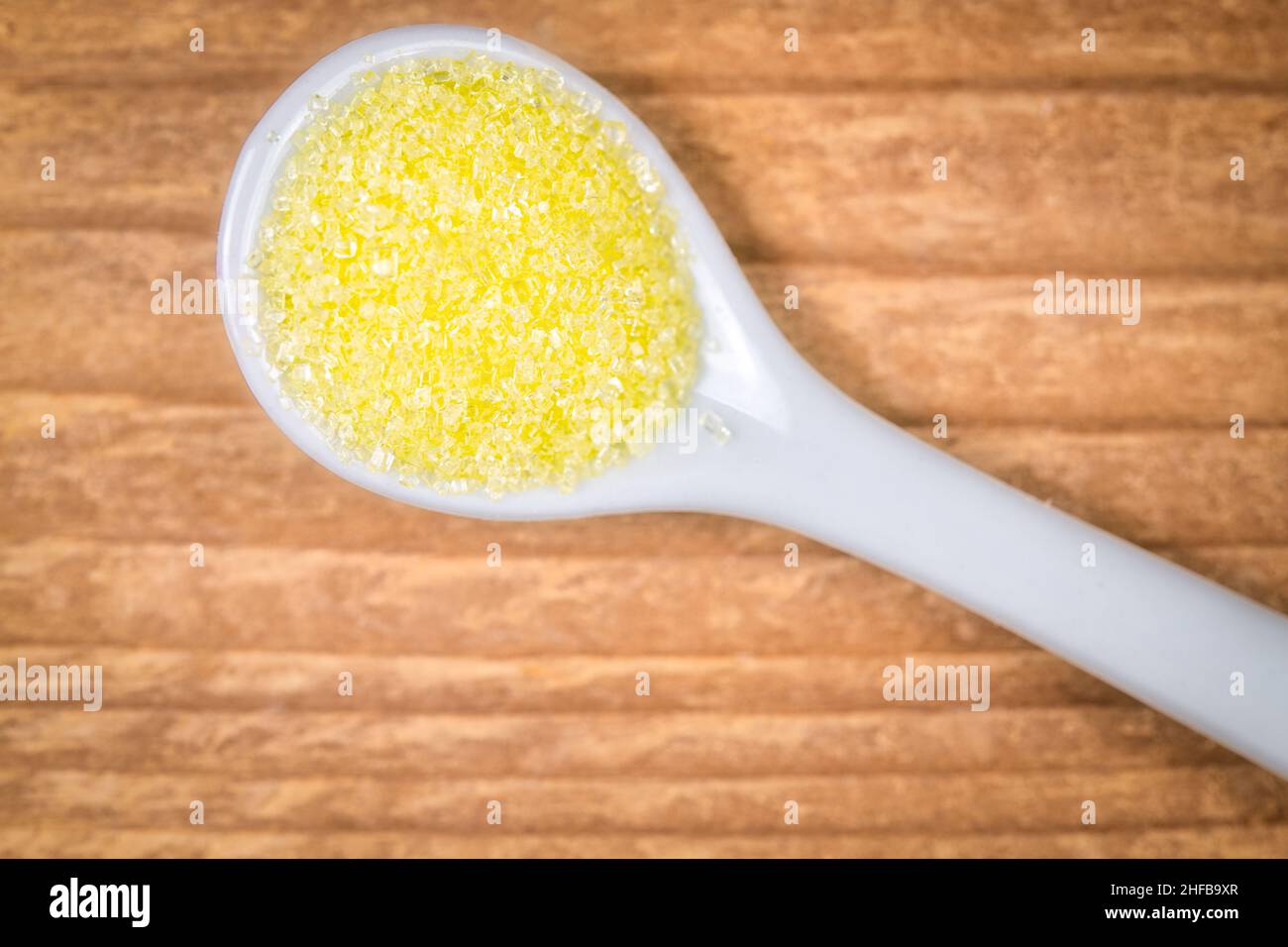 Süßer, gelber Zucker in einem weißen Löffel Stockfoto