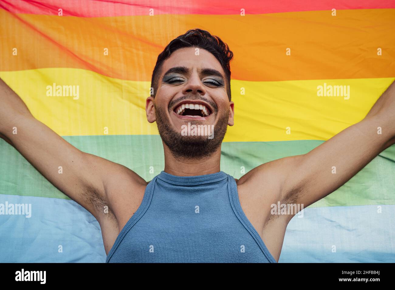 Glücklicher homosexueller Mann feiert Homosexuell Stolz mit Regenbogenflagge Symbol der LGBTQ Gemeinschaft Stockfoto