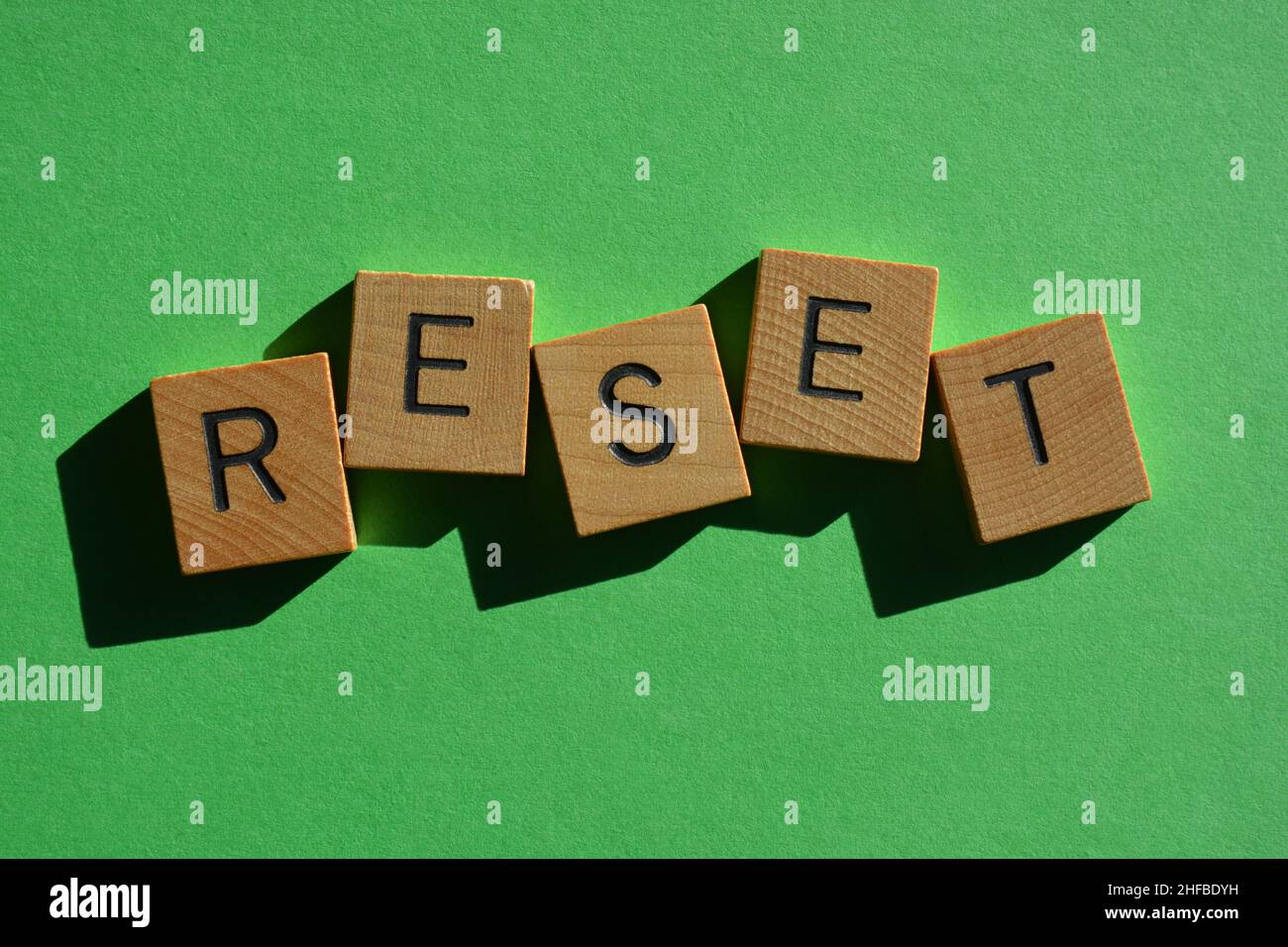 Reset, Wort in Holzbuchstaben isoliert auf hellgrünem Hintergrund Stockfoto