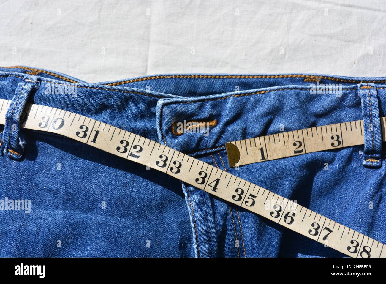 Ernährung und Gewichtsverlust. Maßband im Bund der blauen Jeans Stockfoto