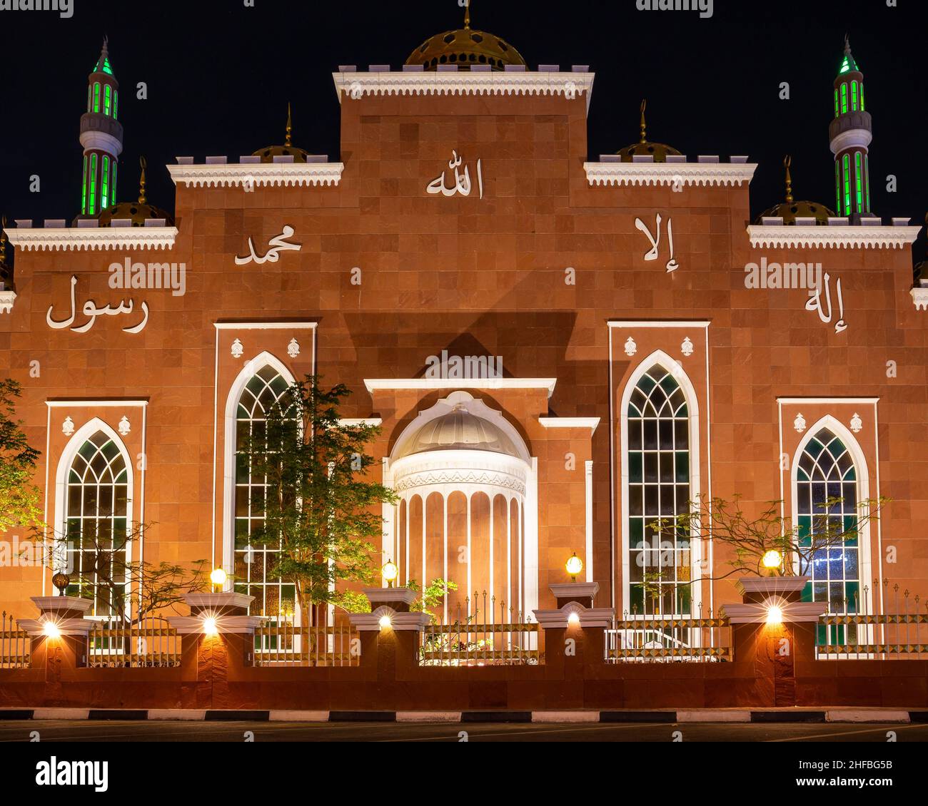 Dubai, VAE, 24.09.21. Al Salam Moschee (Masjid) rote Fassade mit goldenen Ornamenten und grün beleuchteten Minaretten in der Nacht, symmetrische Ansicht. Stockfoto