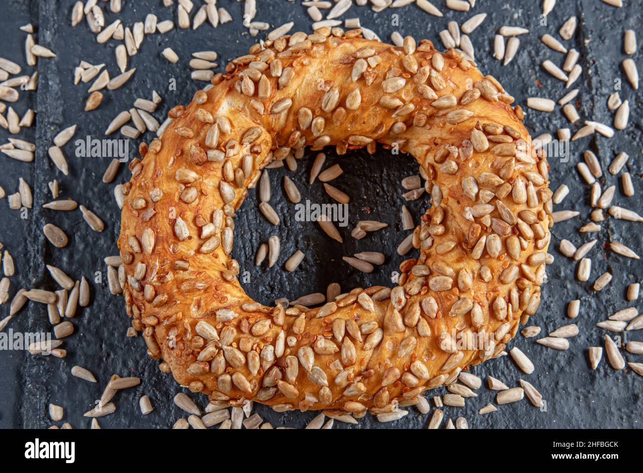 Bagel mit Sonnenblumenkernen auf schwarzem Hintergrund mit Sonnenblumenkernen. Türkischer Simit, knusprig. Stockfoto