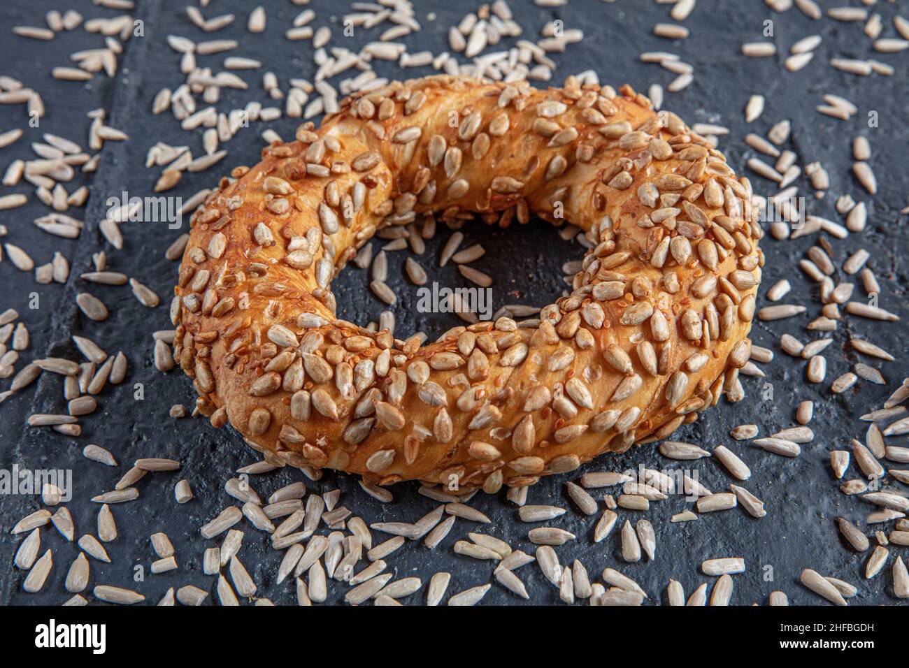 Bagel mit Sonnenblumenkernen auf schwarzem Hintergrund mit Sonnenblumenkernen. Türkischer Simit, knusprig. Stockfoto