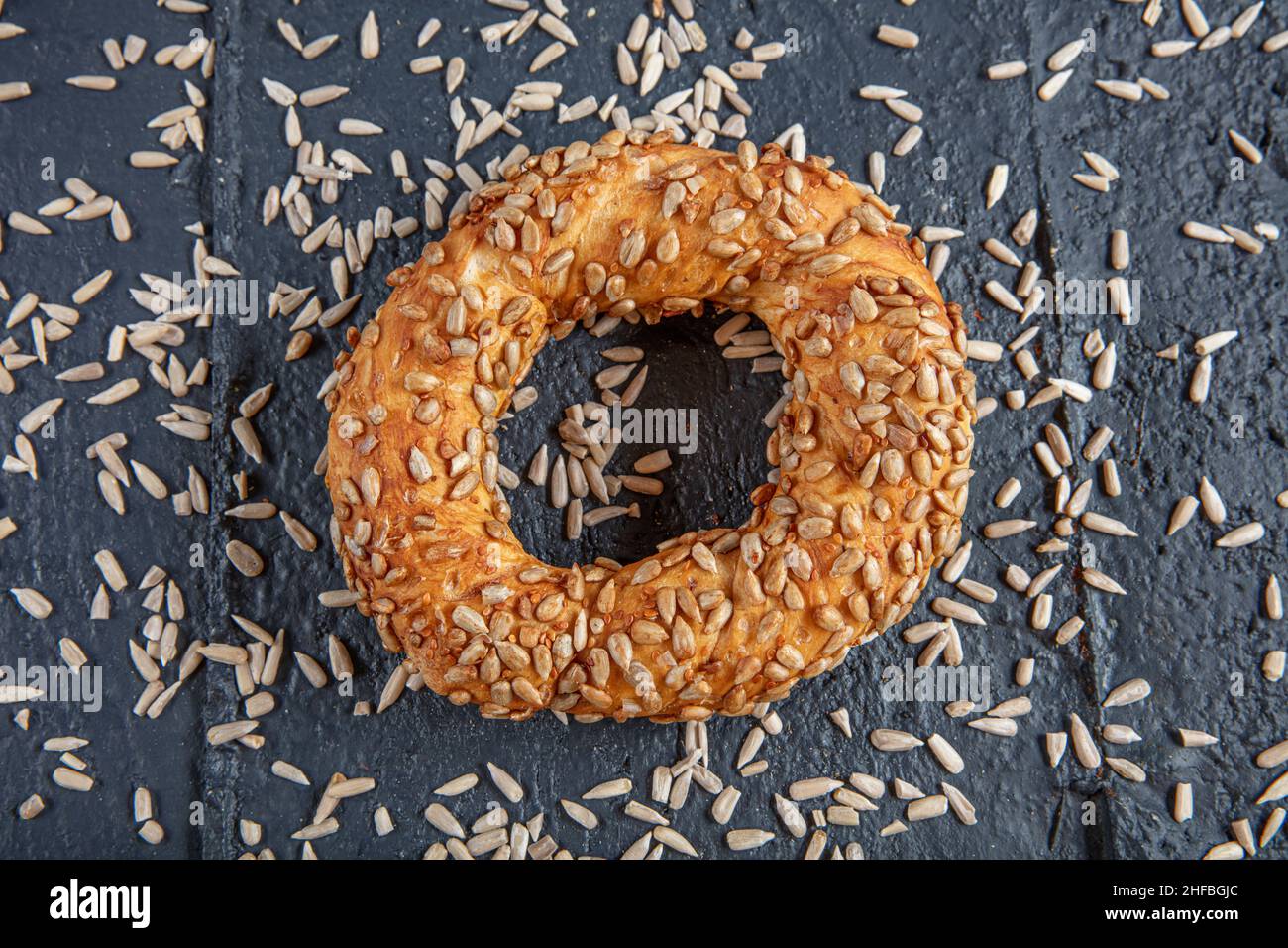 Bagel mit Sonnenblumenkernen auf schwarzem Hintergrund mit Sonnenblumenkernen. Türkischer Simit, knusprig. Stockfoto