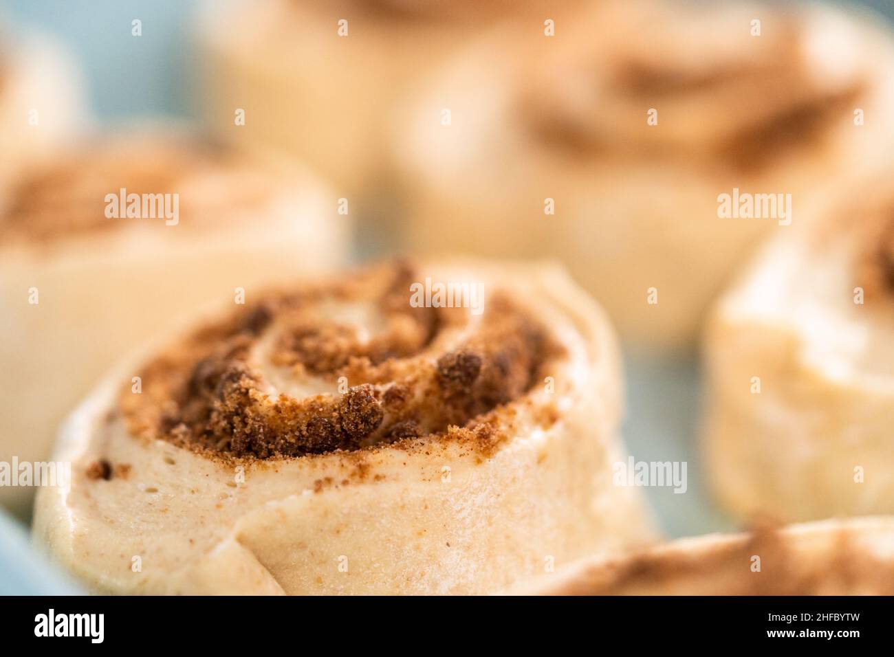 Ungebackene Zimtbrötchen in einer blauen Backform. Stockfoto