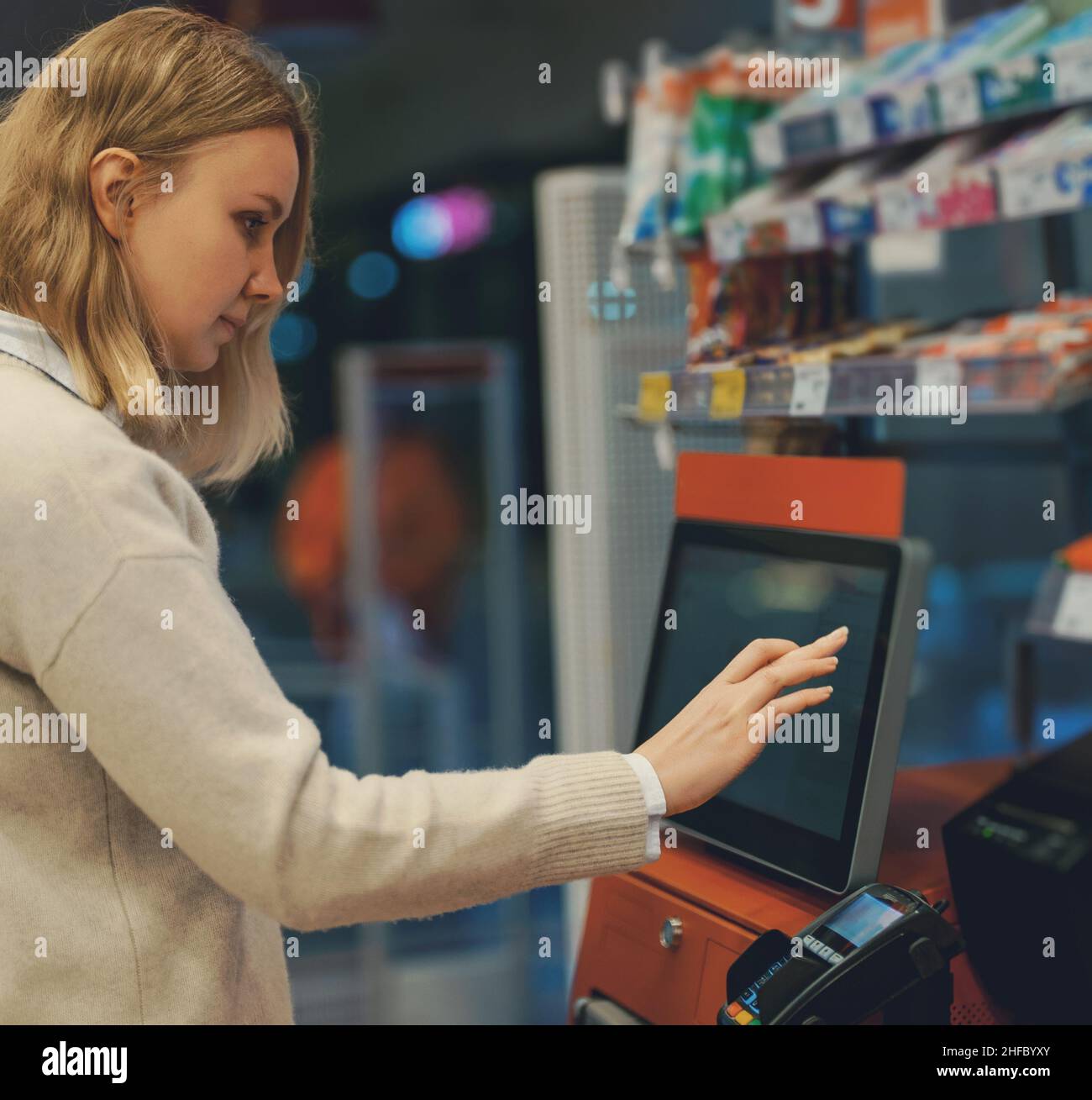 Frau zahlt an Selbstcheckouts im Supermarkt. Stockfoto