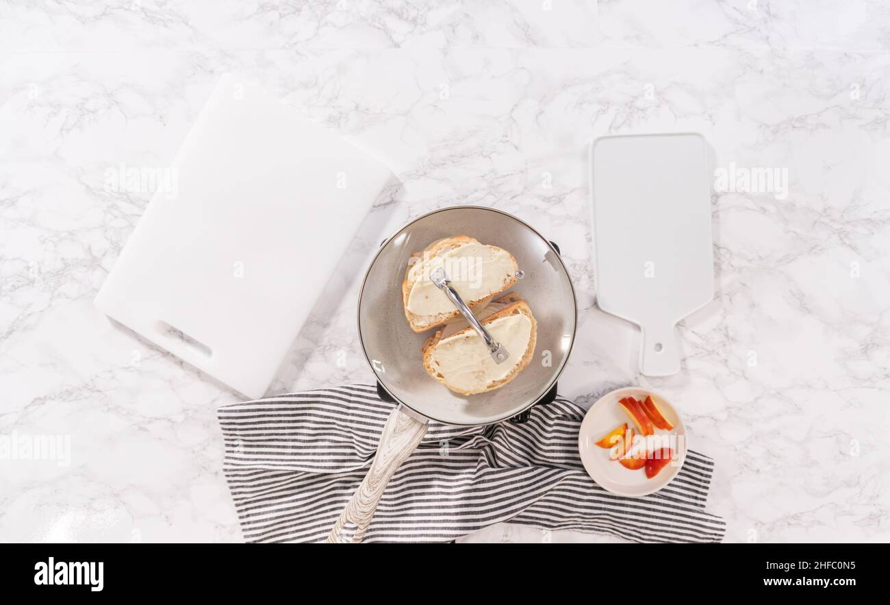 Flach liegend. Bereiten Sie auf einer antihaftbeschichteten Bratpfanne ein vom Apfel und Provolone gegrilltes Käse-Sandwich zu. Stockfoto