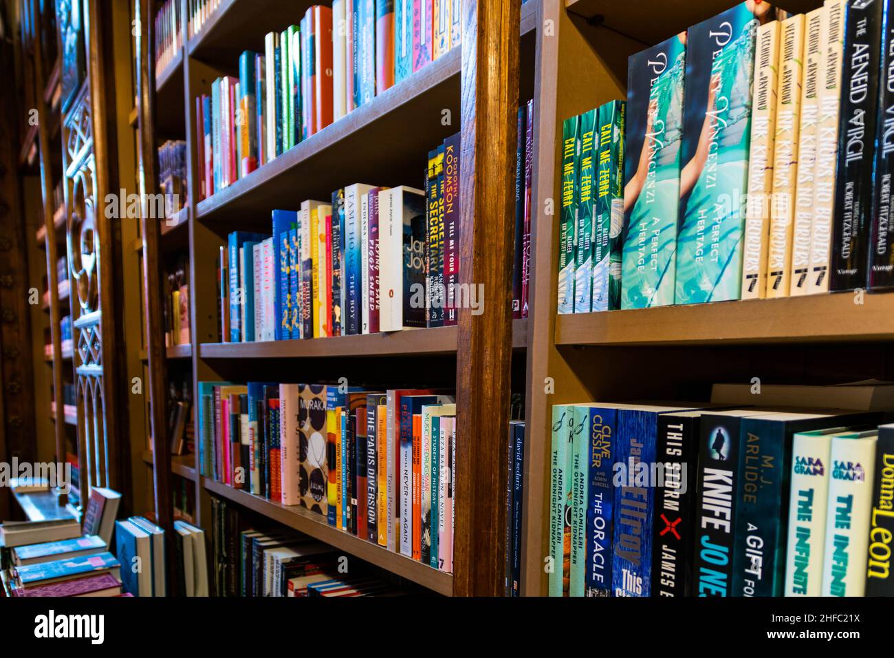Porto, Portugal - 18 Nov 2020: Eine Vielzahl von Büchern, die ordentlich und ordentlich auf einem Holzregal in einem Buchladen oder einer Bibliothek gestapelt sind. Organisationskonzept, Stockfoto