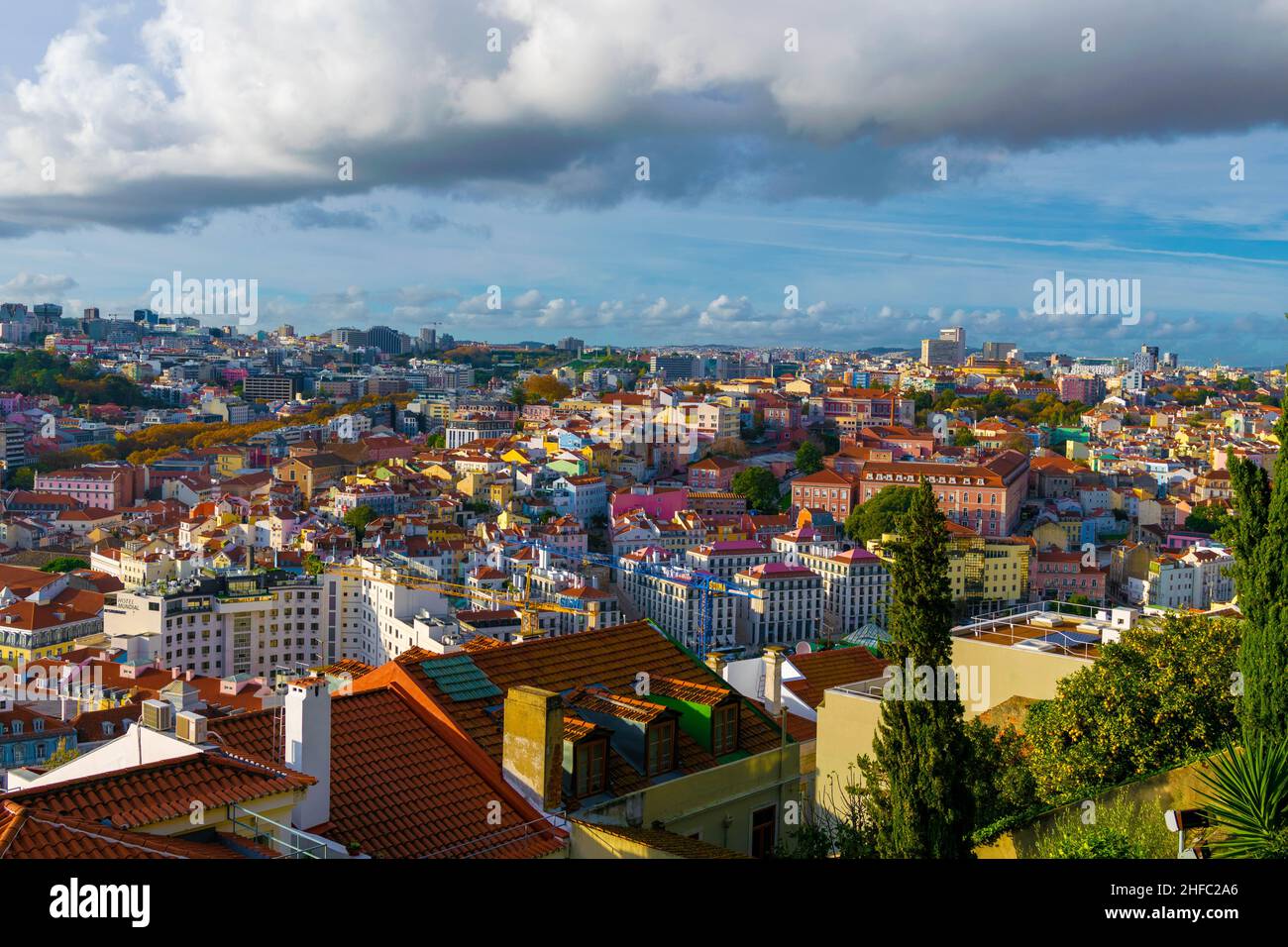 Lebhafte und farbenfrohe Postkartenansicht über Lissabon, Portugal. Orangefarbene Dächer, grüne Bäume und farbenfrohe Gebäude an einem Sommertag. Reisen, besuchen Stockfoto