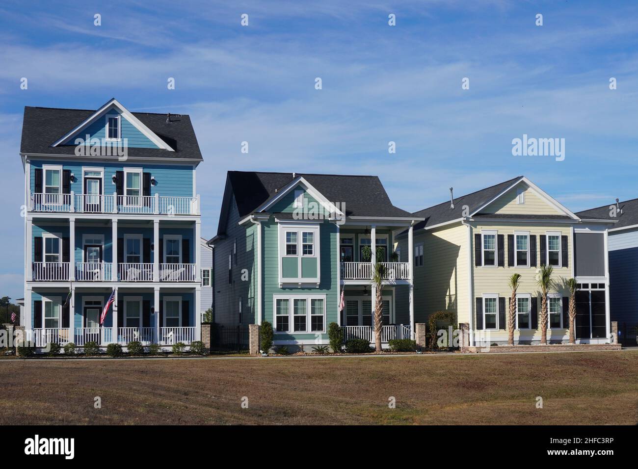 Blaue, grüne und gelbe Häuser in einer Reihe in einem Vorburbanviertel in South Carolina Stockfoto