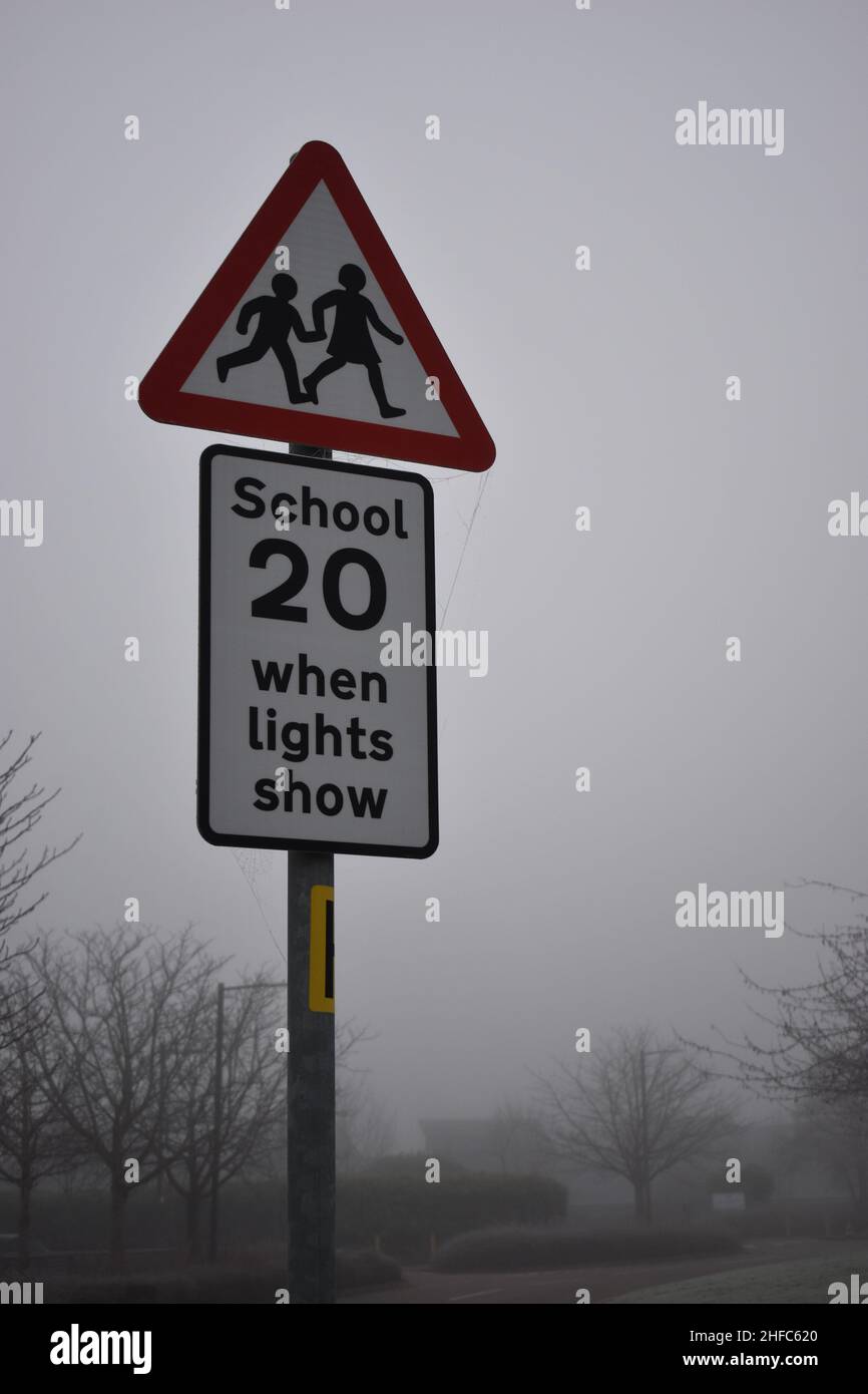 Warnschild warnt vor einer Geschwindigkeitsbegrenzung von 20 km/h. „Schule 20, wenn die Lichter leuchten.“ Stockfoto