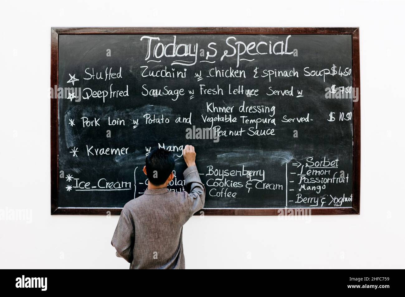 Ein Server schreibt die Tagesangebote auf einer Tafel im FCC Angkor Kitchen, FCC Angkor Hotel, Siem Reap, Kambodscha. Stockfoto