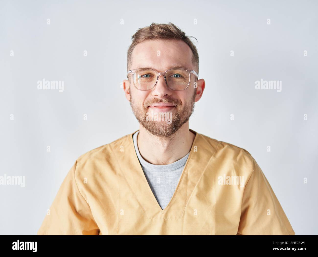 Nahaufnahme eines männlichen Arztes oder einer Krankenschwester mit seinen Armen, die eine Brille hochheben. Porträt eines hübschen kaukasischen männlichen Arztes mit Brillen und beigefarbener medizinischer Uniform. Hochwertige Fotos Stockfoto