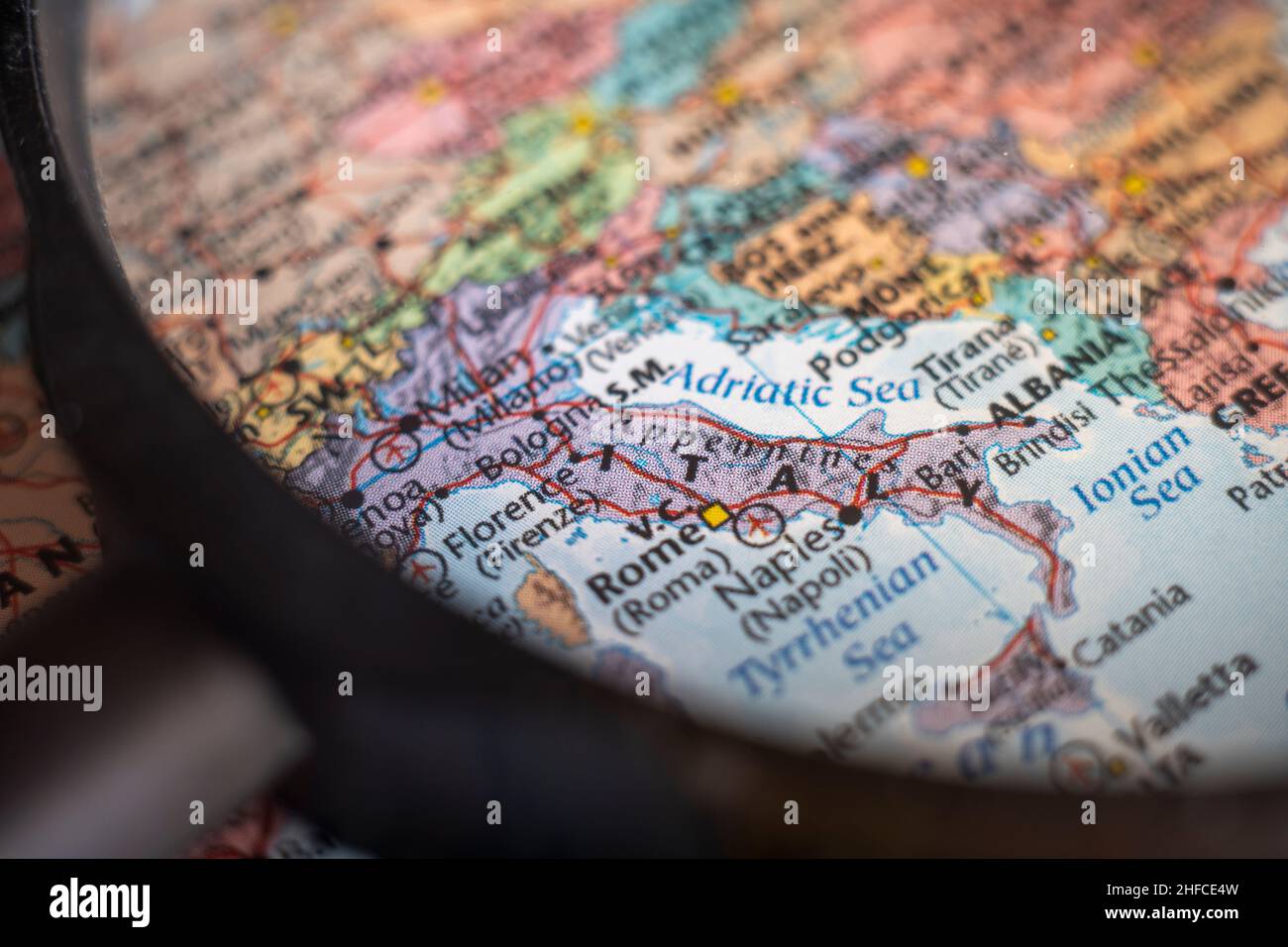 Italien auf einer Weltkarte durch Lupe. Planung von Reisedestination für Italien festgeklemmt Stockfoto