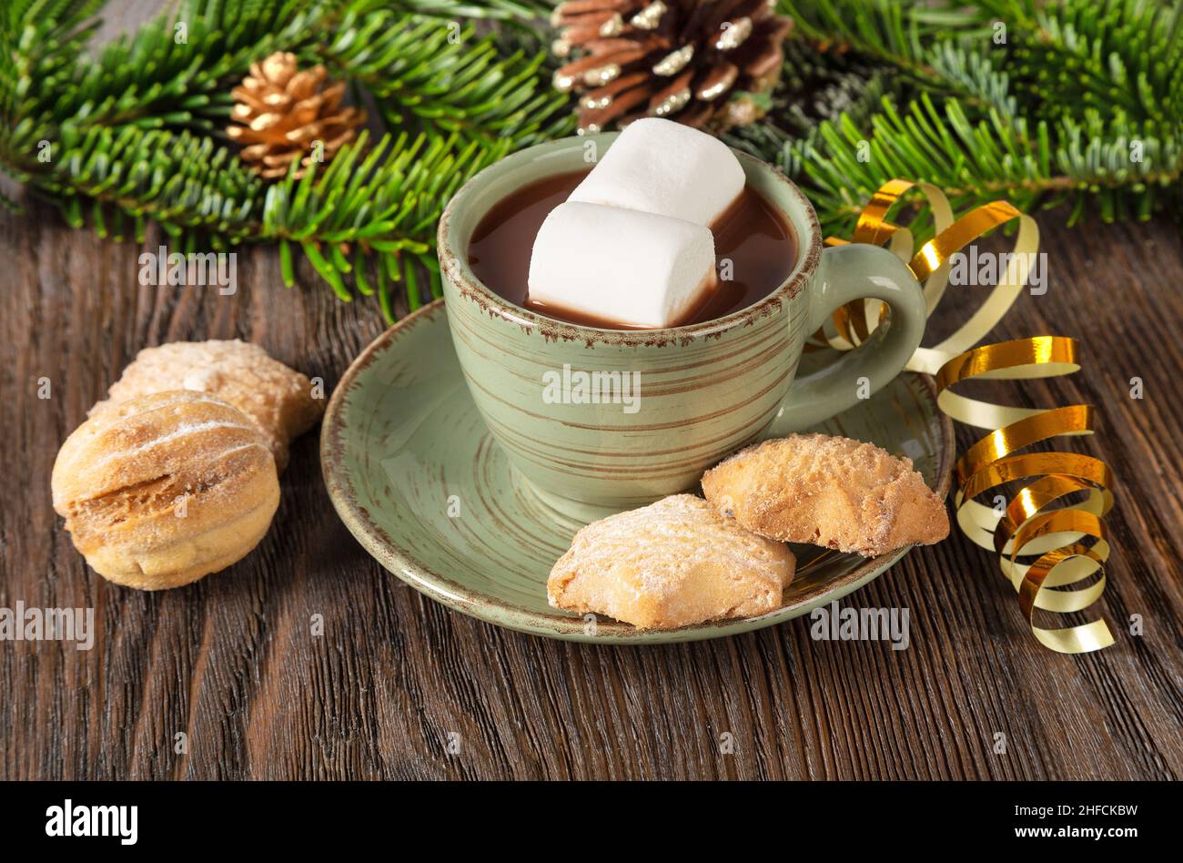 Heiße Schokolade, traditionelles Weihnachtskakaogetränk, süße Kekse und Dekorationen auf braunem Holzhintergrund. Stockfoto