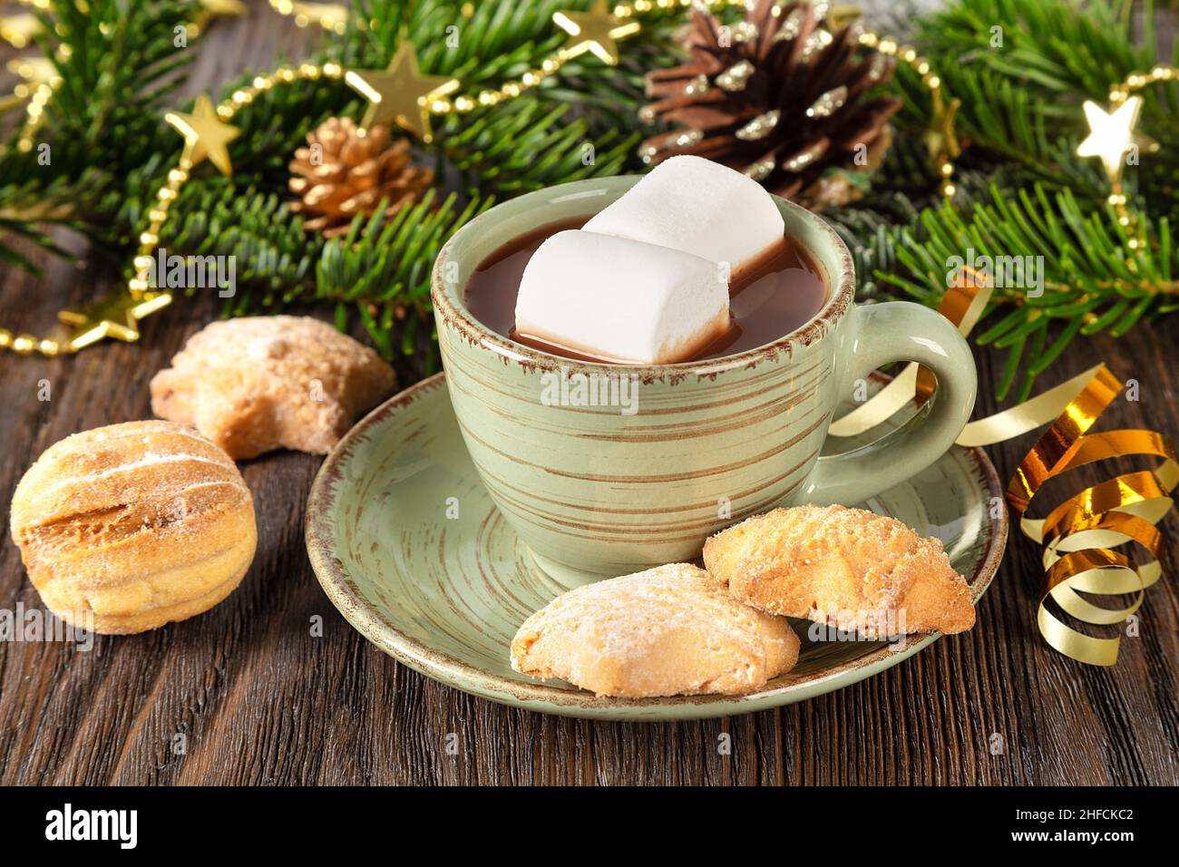 Heiße Schokolade, traditionelles Weihnachtskakaogetränk, süße Kekse und Dekorationen auf braunem Holzhintergrund. Stockfoto